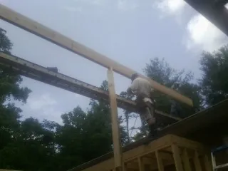 Carpenter setting a ridge beam over a new addition frame — Ice Dam Removal by Roofing Brothers in Colona