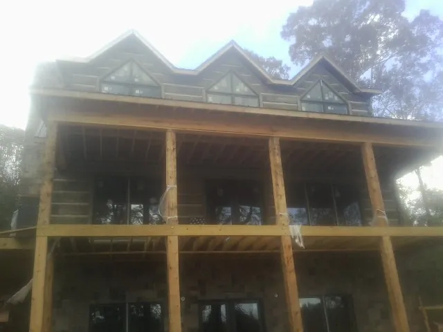 Dormers and porch framing on a large log home under construction — Roof Coating work by our crew in Colona