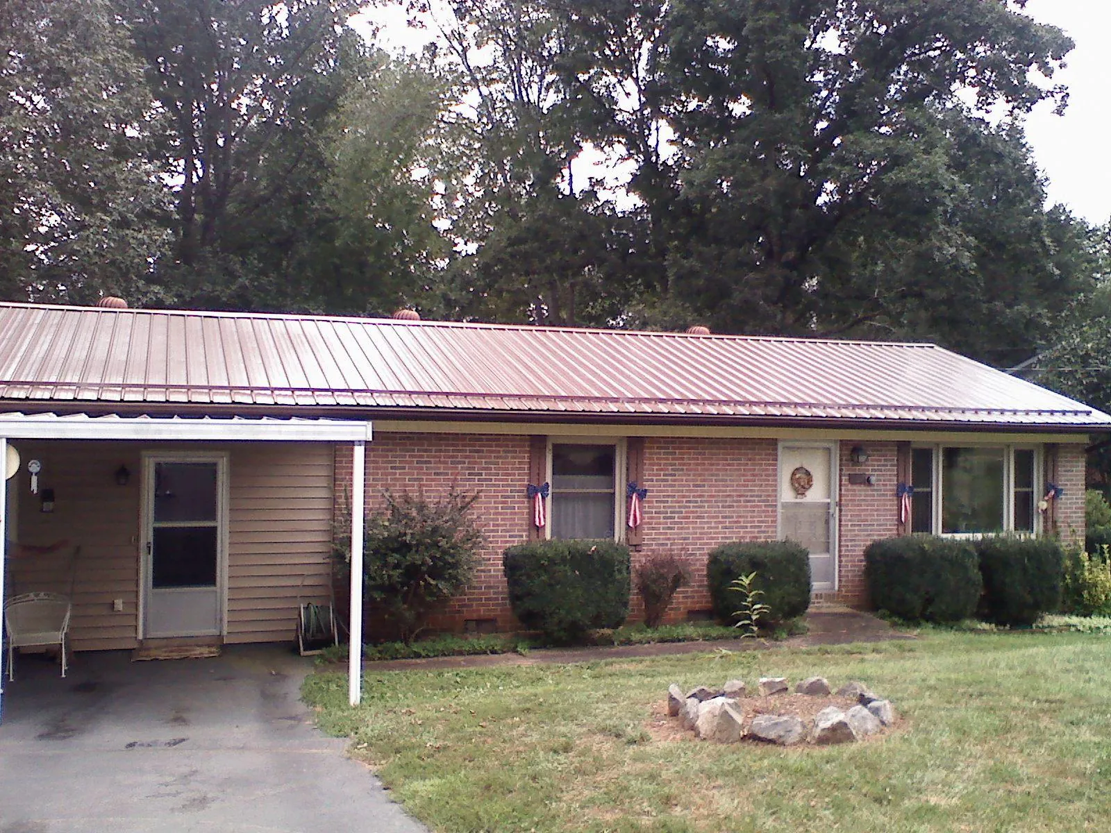 Bronze metal roof and carport on a brick ranch home — Roof Repair work by our crew in Colona