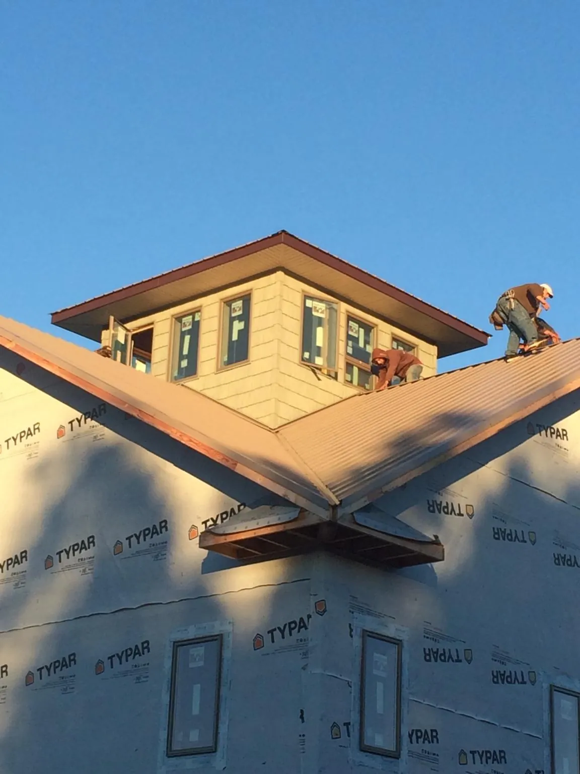 Roofers working around a rooftop cupola on a new metal roof at sunset — Roof Waterproofing in Colona by Roofing Brothers
